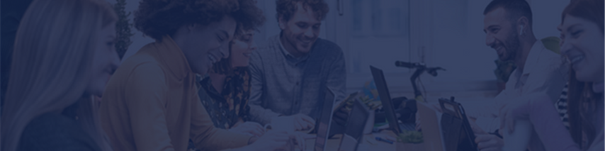 Group of younger business people talking and laughing around table with laptops