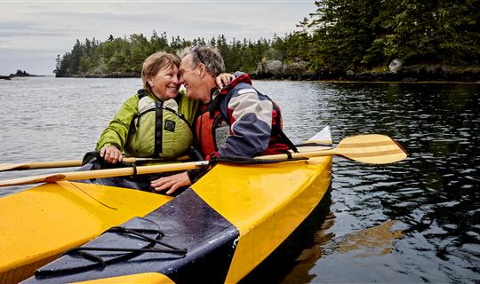 Man and woman in kayak smiling and hugging