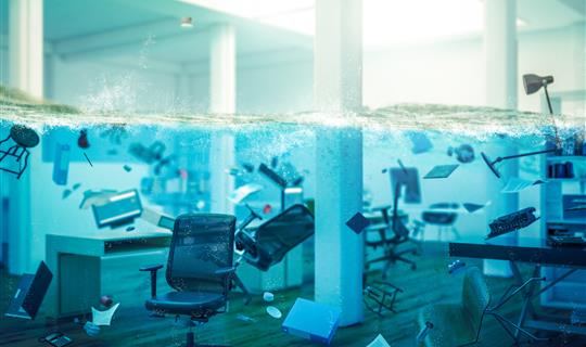 Office flooded with chairs and technology floating in water