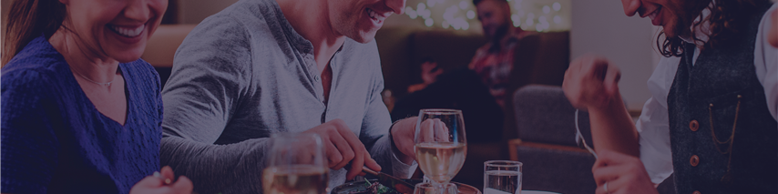 Group of people eating and drinkin in restaurant around table